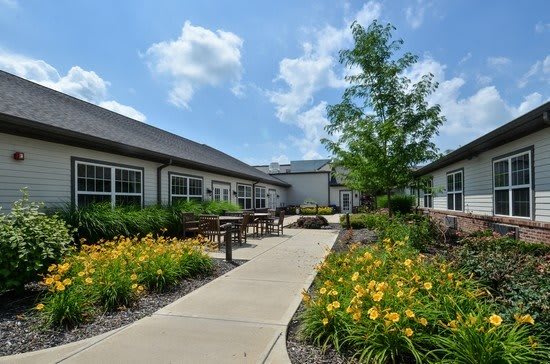 A beautifully landscaped garden with a pathway leading to adjacent buildings under a bright, sunny sky.
