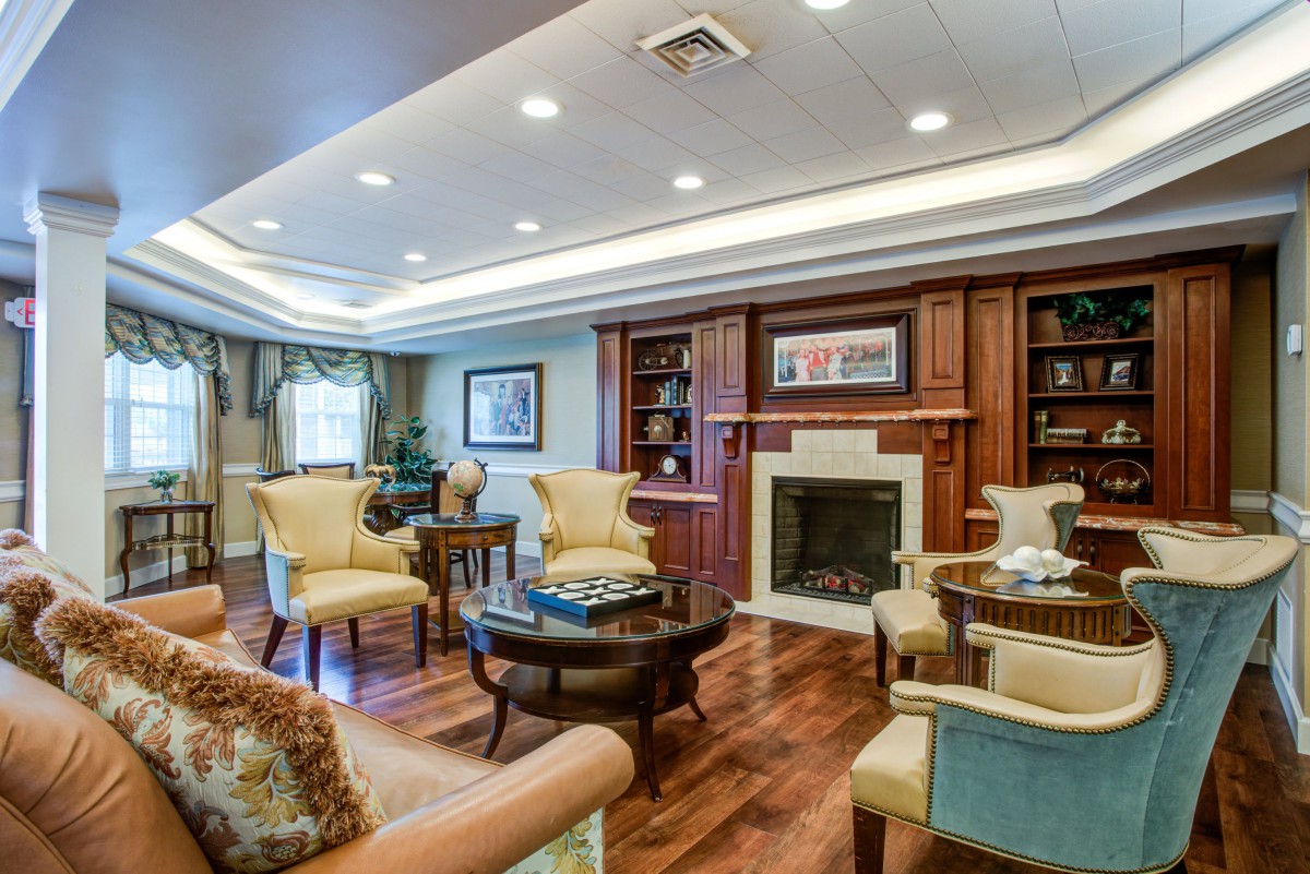 A cozy and elegantly designed living room featuring a fireplace, comfortable seating, and wooden bookshelves.