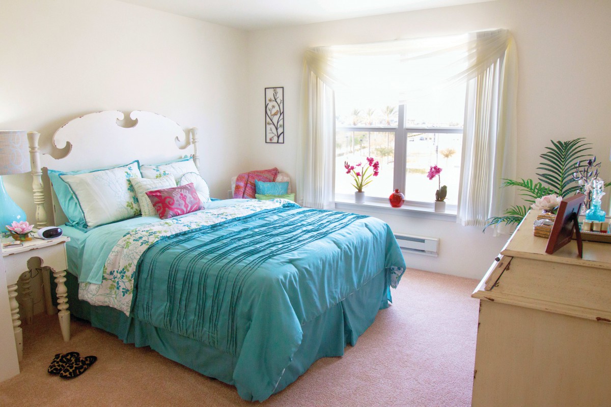 A bright and cozy bedroom with a teal comforter and colorful decor.
