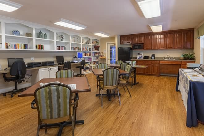 A cozy kitchen and dining area with tables, chairs, cabinets, and bookshelves.