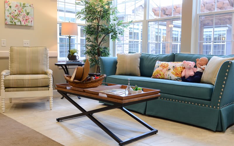 A cozy living room with a teal sofa, stylish coffee table, and warm natural light.