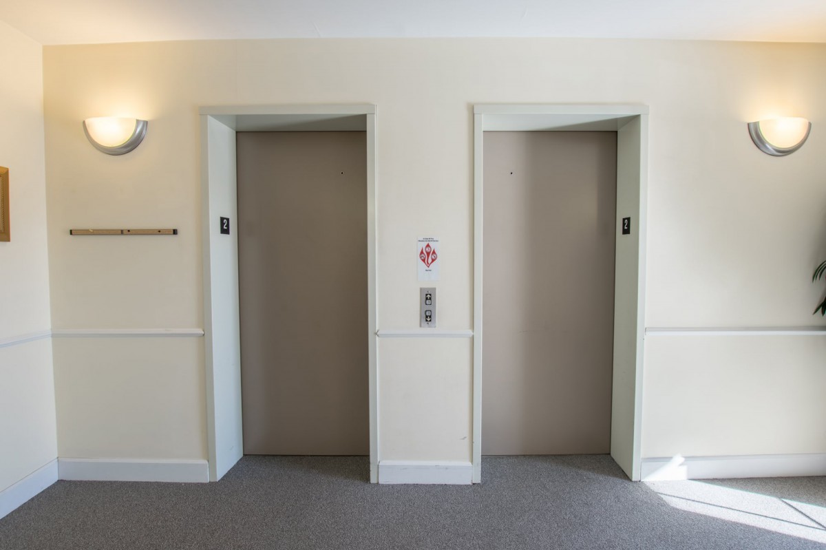 Two elevator doors in a building interior, one open and one closed.