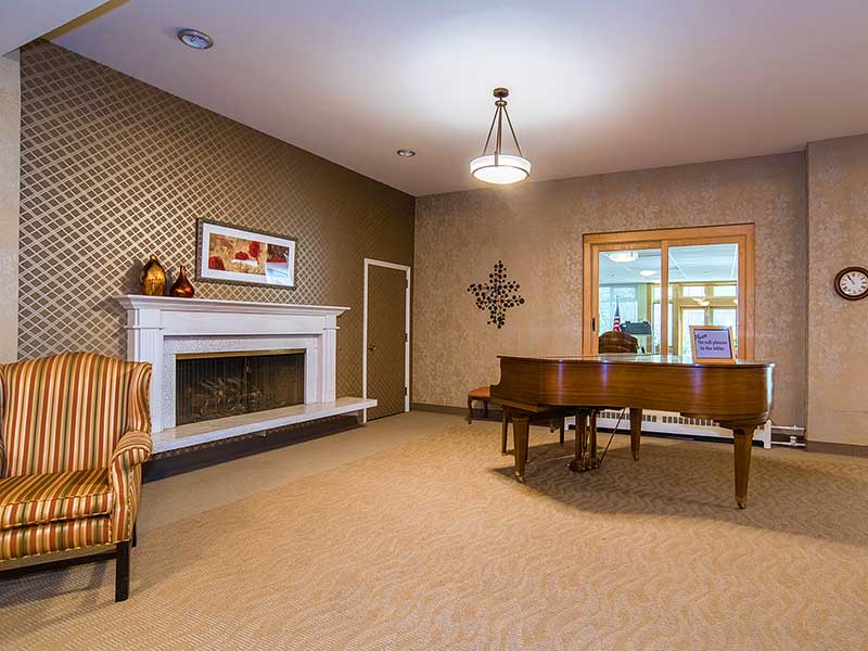 A cozy living room featuring a grand piano and a fireplace.