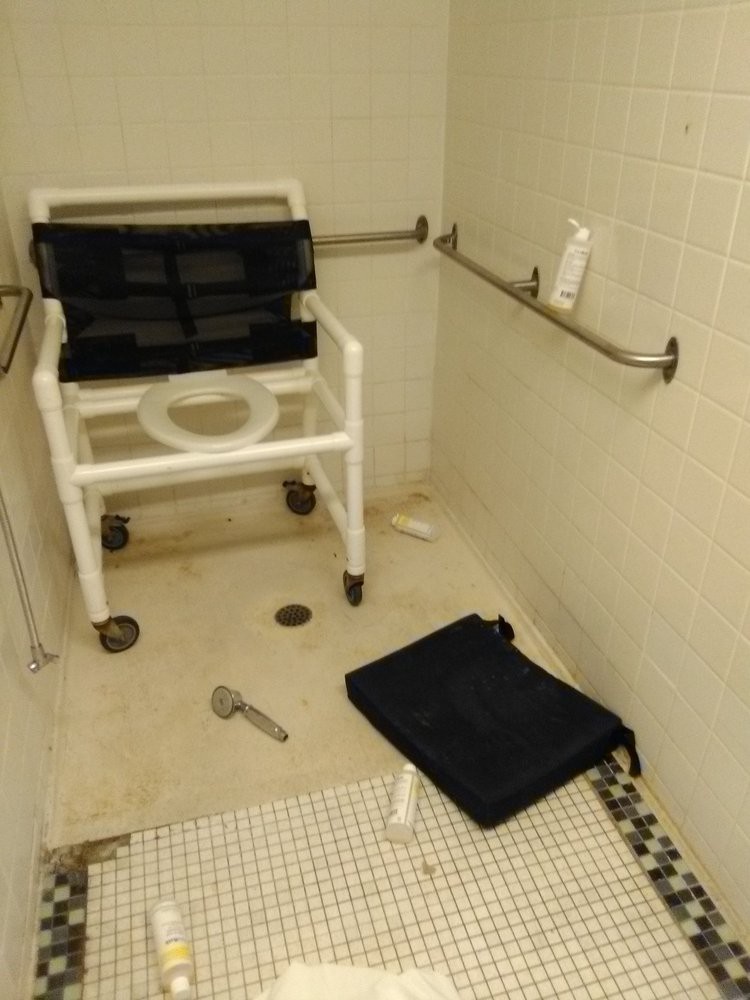 An accessible shower area with a wheelchair and safety handrails.