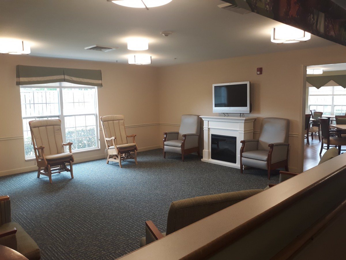 A spacious living room with seating, a fireplace, and a television.