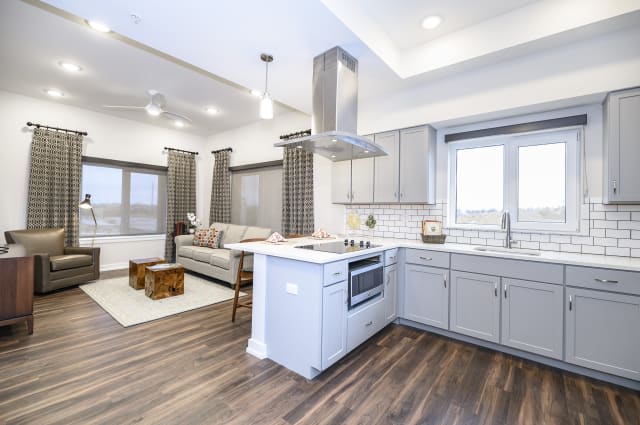 A modern open-concept kitchen and living room with stylish white cabinets and hardwood floors.