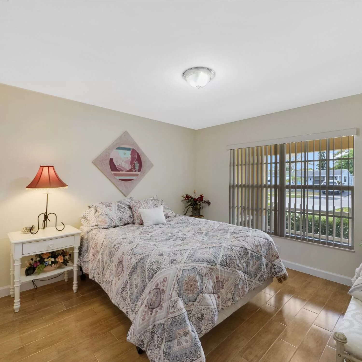 A cozy bedroom with a bed, nightstand, and window allowing natural light.