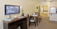 A cozy living and dining area with a small dining table, chairs, a television, and decorative items.