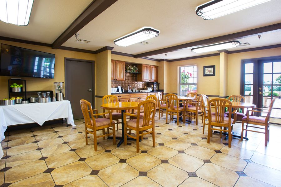 A cozy dining area with wooden tables and chairs, featuring a coffee station and tiled flooring.
