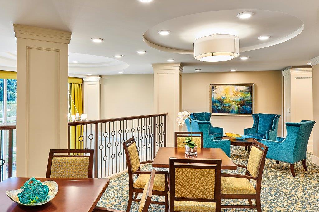 A well-lit, elegantly furnished living area featuring a dining table and lounge chairs.