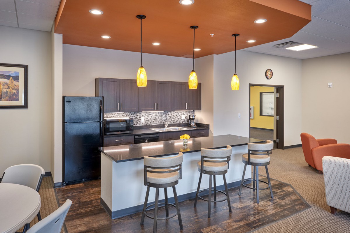 A modern kitchen interior with an island and bar stools, featuring pendant lighting and appliances.