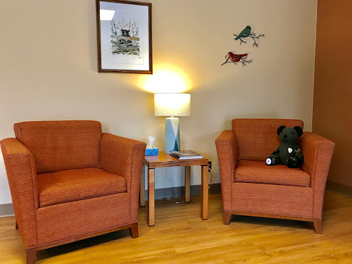 A cozy living room corner featuring orange chairs, a side table with a lamp, and playful wall art.