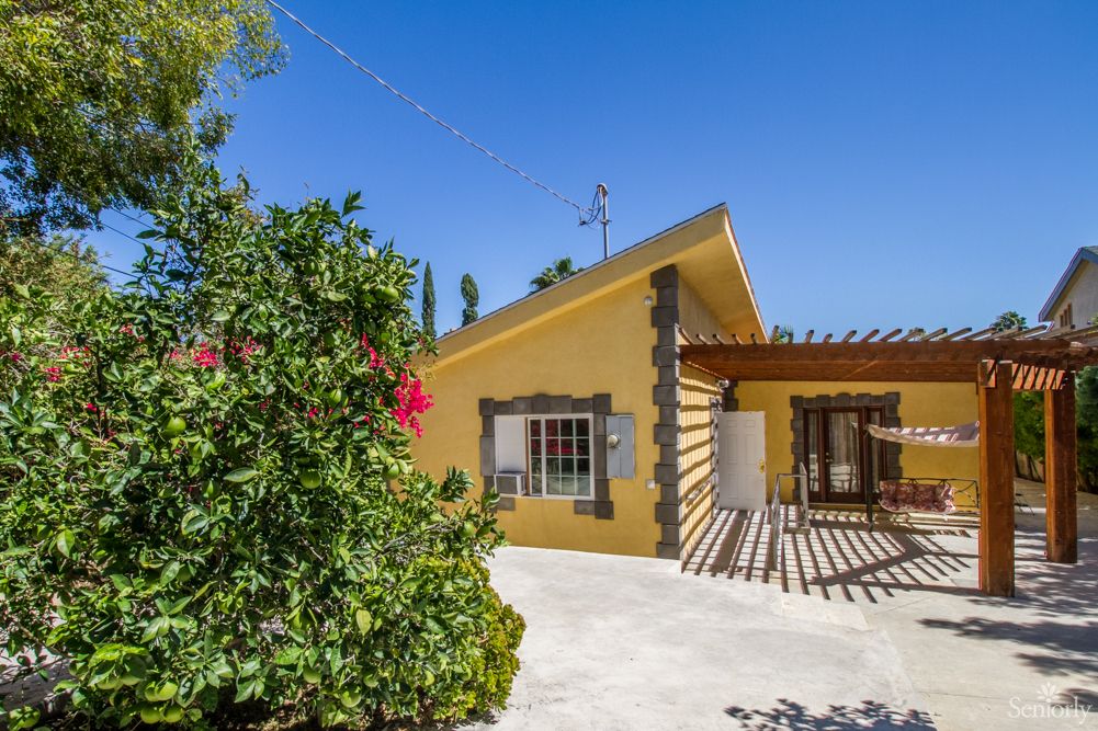 A charming yellow house with a garden in a sunny outdoor setting.