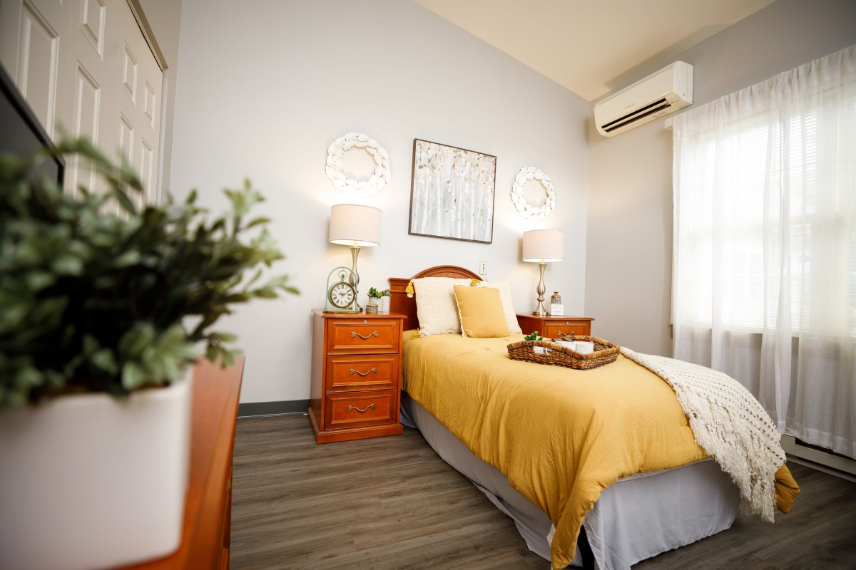 A cozy bedroom with a single bed, wooden nightstands, and warm lighting.