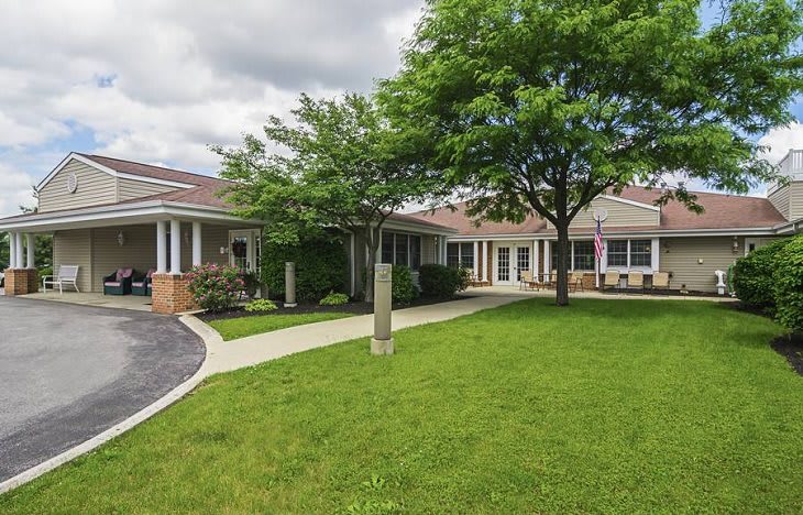 A school building with a grassy lawn and trees on a cloudy day.