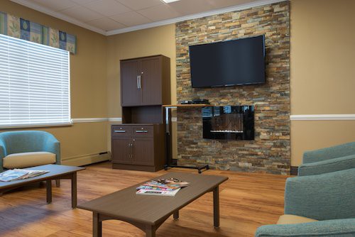 A modern living room featuring a stone accent wall with a mounted TV and fireplace, complemented by wooden flooring and sleek furniture.