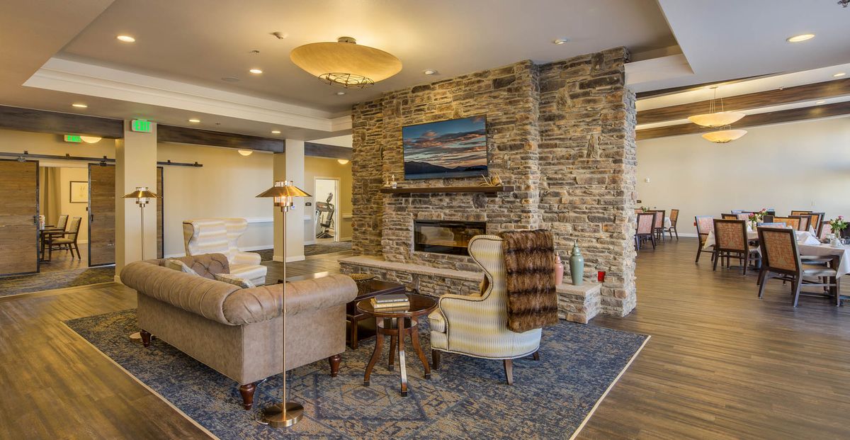 A cozy living room with a stone fireplace, comfortable seating, and warm lighting.