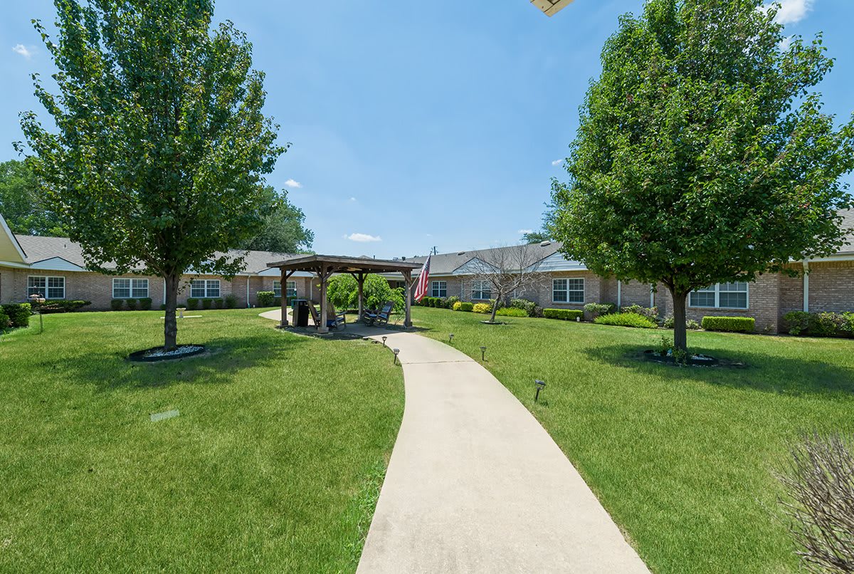 A scenic garden path leads to a pavilion surrounded by greenery.