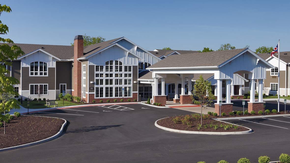 A modern residential building with a spacious entrance and landscaped parking area.