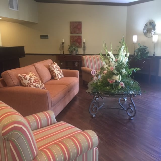 A cozy living room setting with comfortable sofas and armchairs, a coffee table adorned with a flower arrangement.
