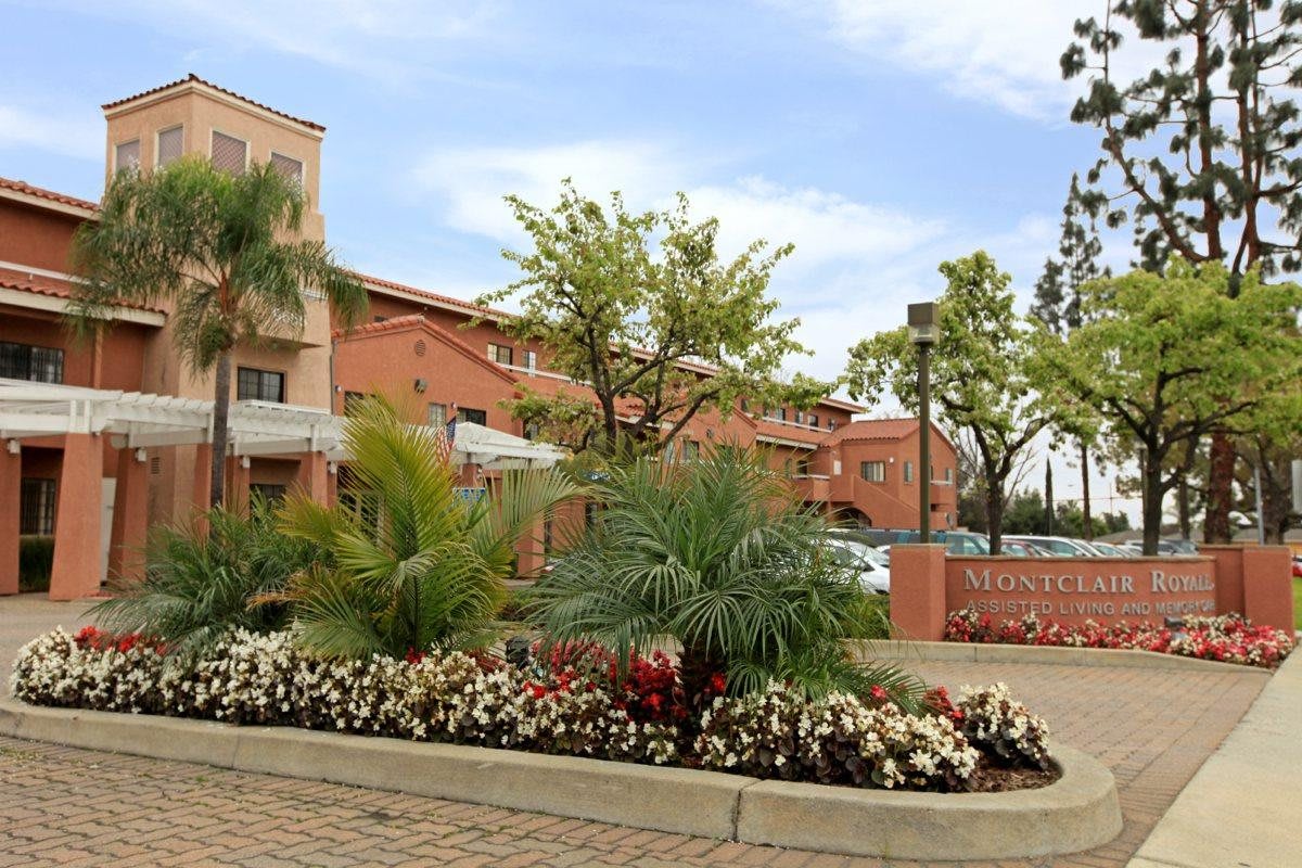 A landscaped residential complex with lush greenery and flowers in the foreground.