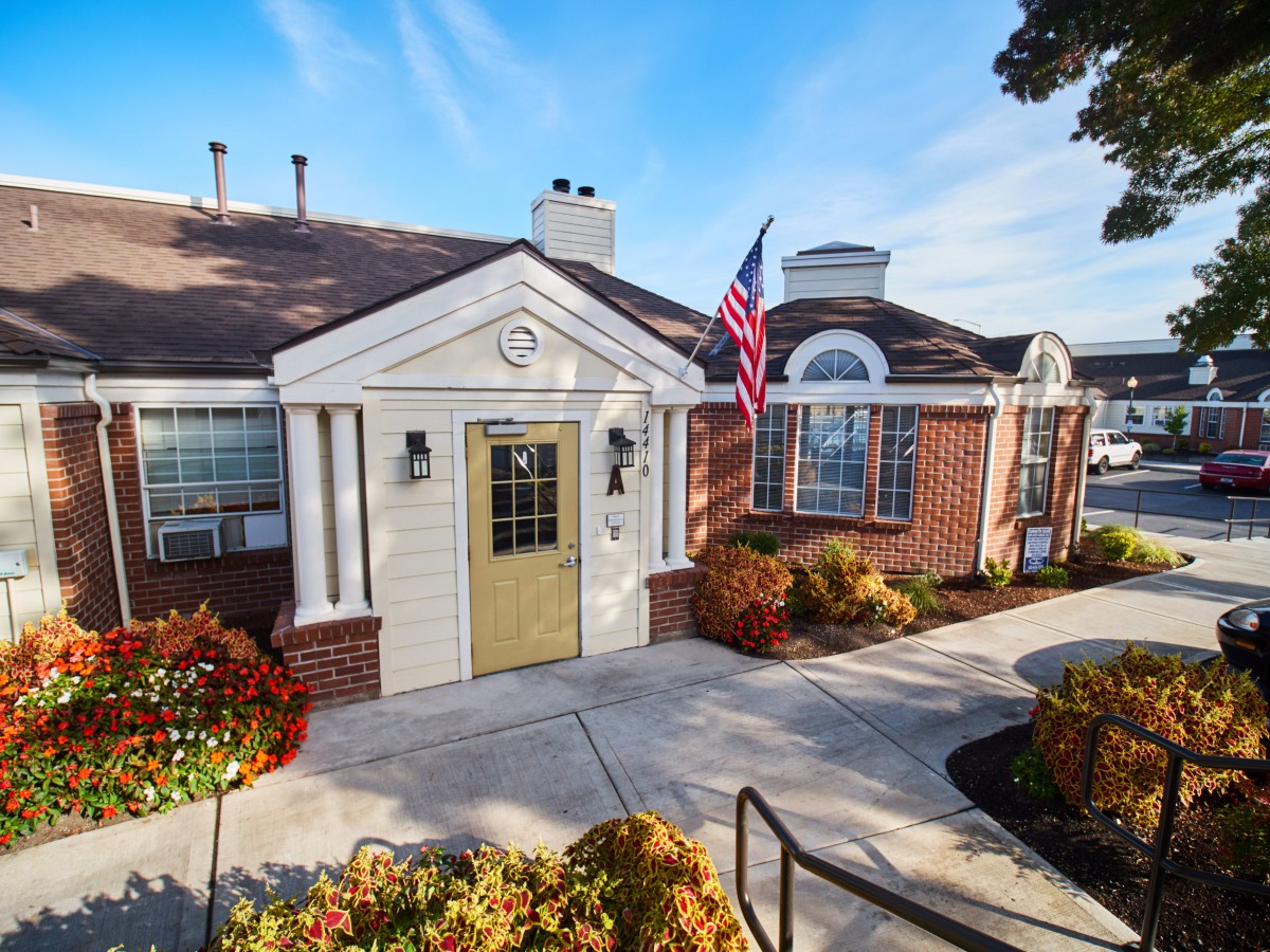 A charming residential building with a landscaped entrance and an American flag displayed.