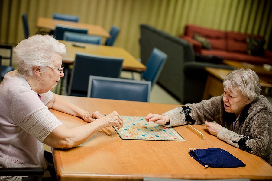 Two elderly individuals engage in a board game at a community center.