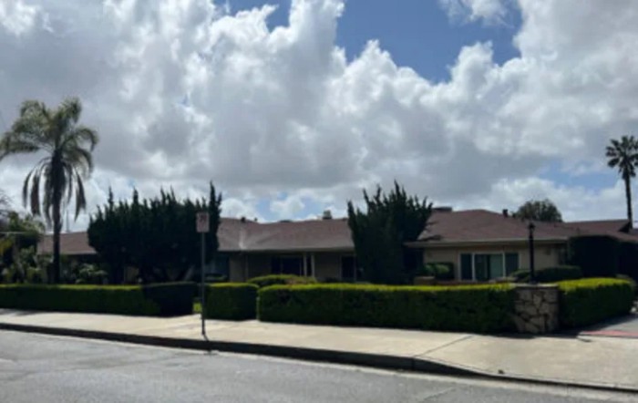 A suburban neighborhood with houses, a sidewalk, and a cloudy sky.