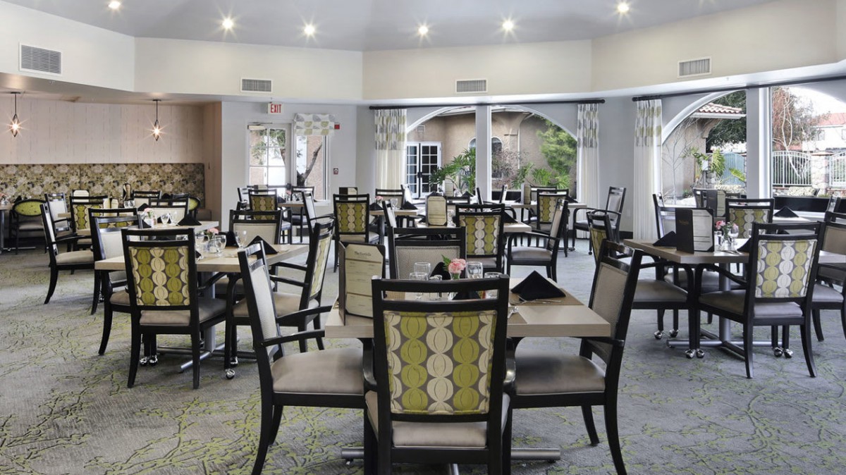 A spacious dining area with neatly arranged tables and chairs, featuring elegant lighting.