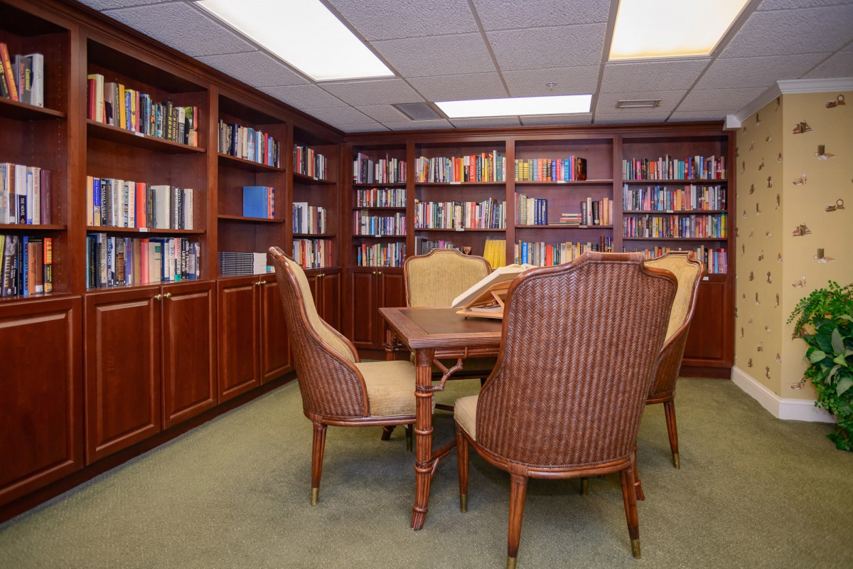 A cozy library corner with a table and chairs surrounded by bookshelves.