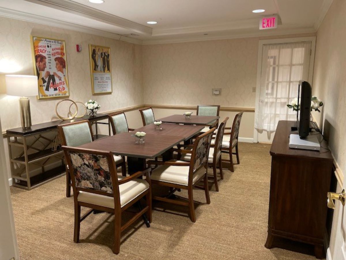 A well-appointed conference room with a large table surrounded by chairs, featuring artwork and decor on the walls.