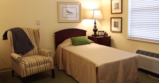 A cozy bedroom with a single bed, nightstand, and lamp.