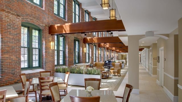 A modern restaurant interior with wooden beams, ample natural light, and a comfortable dining area.
