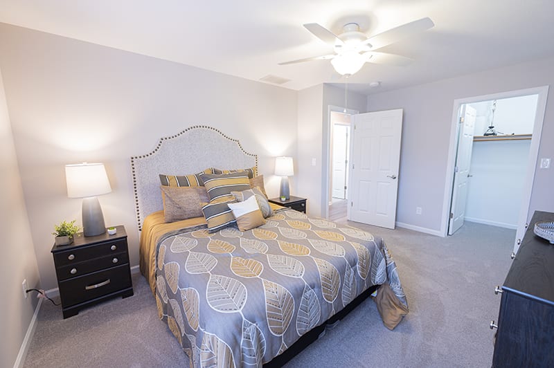 A modern bedroom with a neatly made bed, nightstands, and soft lighting.