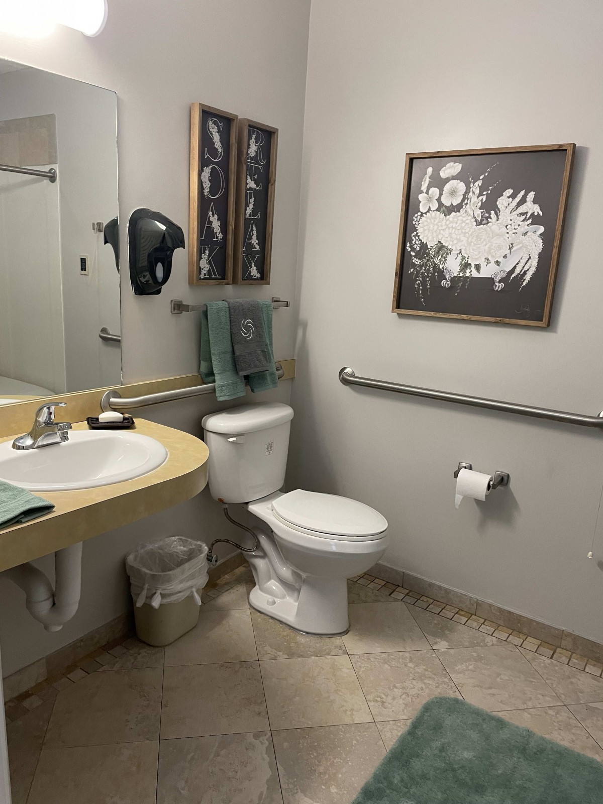A clean and well-organized bathroom with a sink, toilet, and wall art.