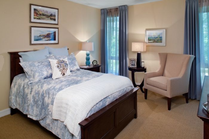 A cozy bedroom with elegant decor, featuring a bed, armchair, and two bedside lamps.