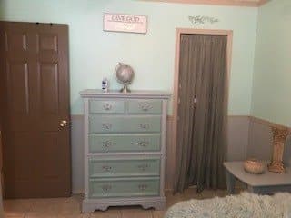 A mint green themed bedroom with a dresser and decorative items.