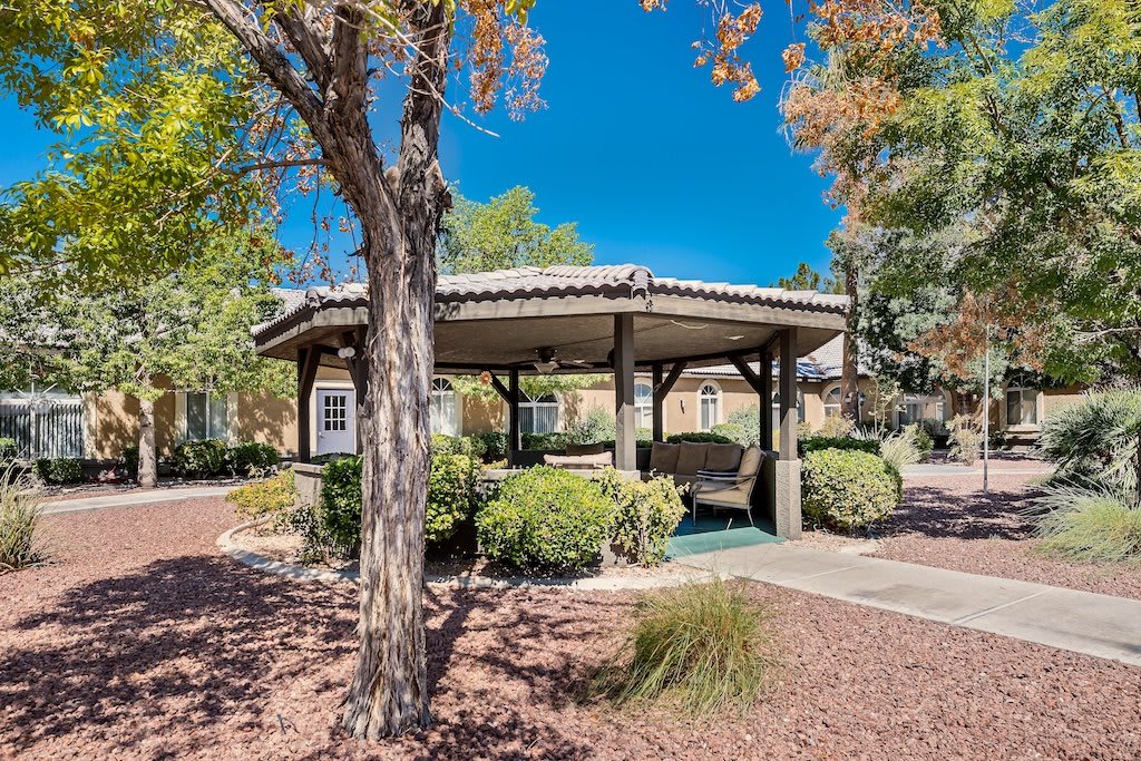 A serene park setting featuring a gazebo surrounded by trees and greenery on a sunny day.
