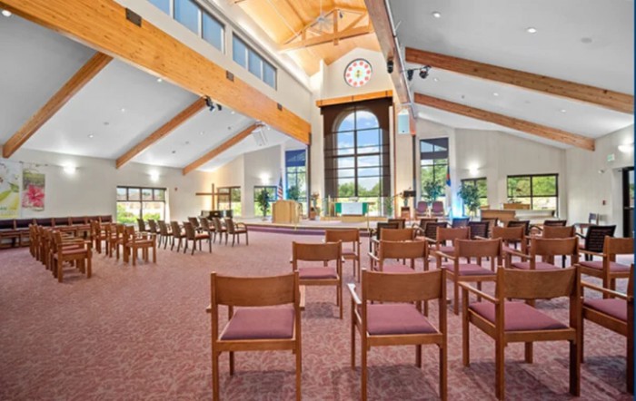 A spacious room with wooden beams, large windows, and neatly arranged chairs.