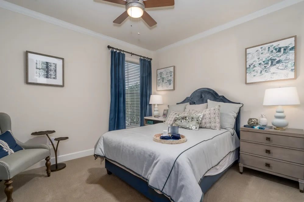A cozy bedroom featuring a blue and white color scheme with a neatly made bed, bedside tables, and elegant decor.