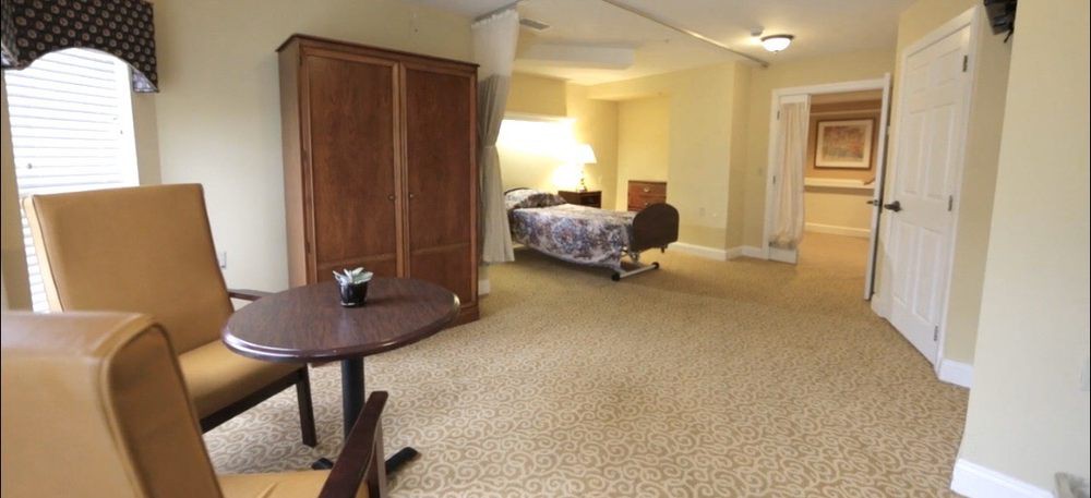 A spacious bedroom with a bed, wooden furniture, and a carpeted floor.