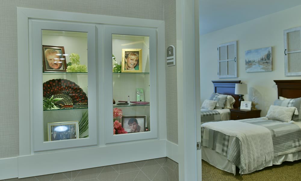 A cozy home interior featuring a bedroom and a display case with photographs.