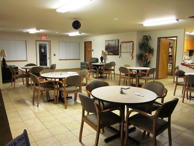 An empty community dining area with round tables and chairs.