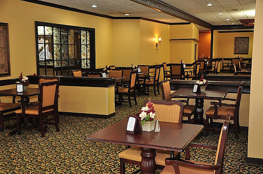 A cozy restaurant dining area with neatly arranged tables and chairs on a carpeted floor.