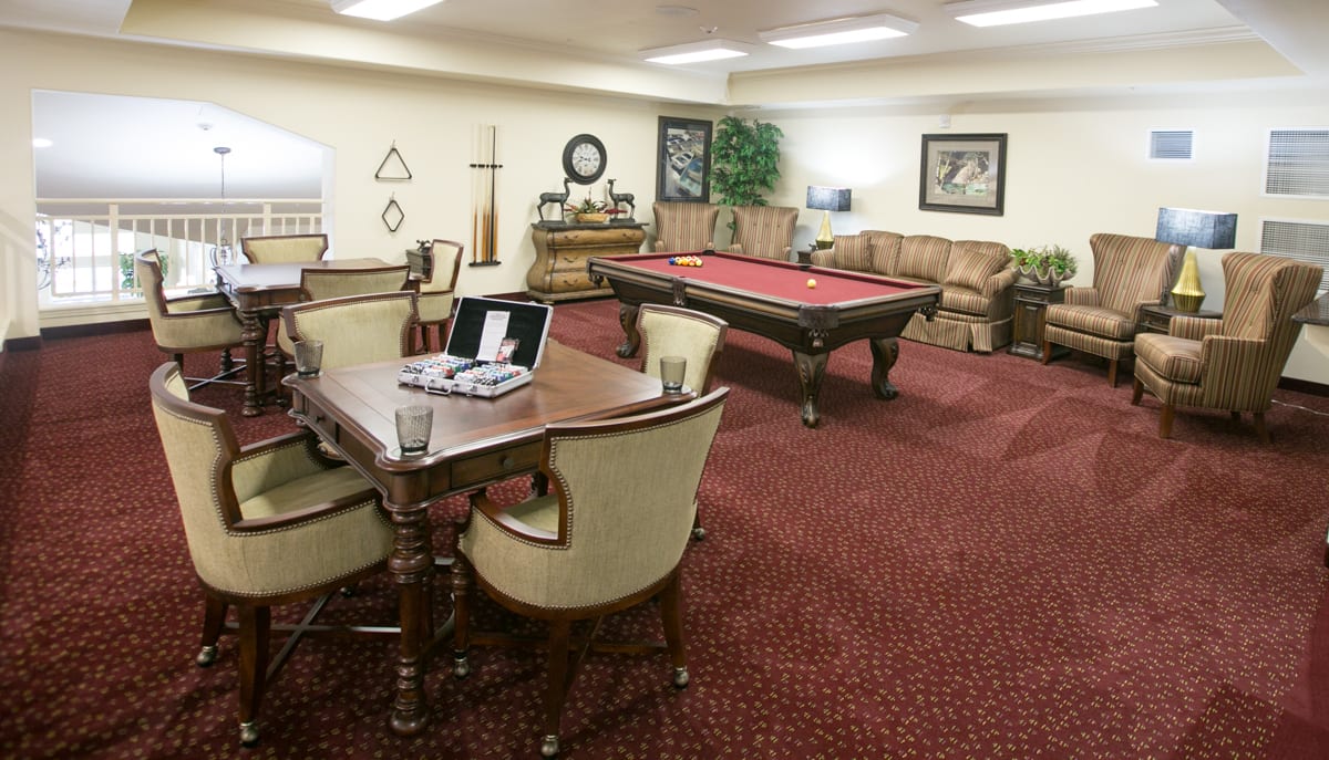 A cozy game room featuring a pool table and a seating area with a laptop on the table.