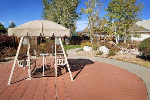 A serene park area featuring a shaded seating space and a winding pathway surrounded by greenery.