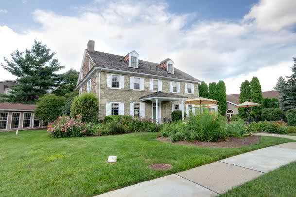 A colonial-style stone house with well-maintained landscaping and a manicured lawn.
