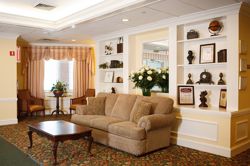 A cozy living room featuring a comfortable sofa, decorative shelves, and fresh flowers.