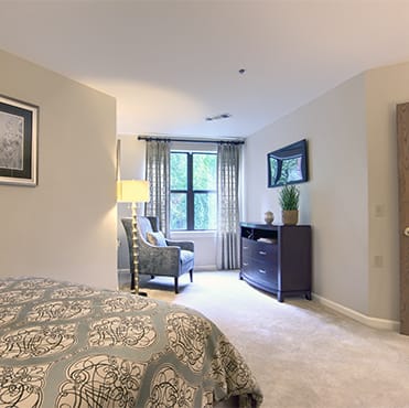 A cozy bedroom with stylish decor and a window allowing natural light in.