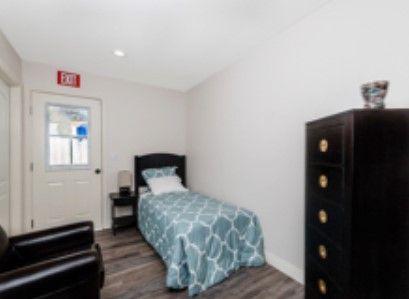 A minimalist bedroom with a single bed and dresser.